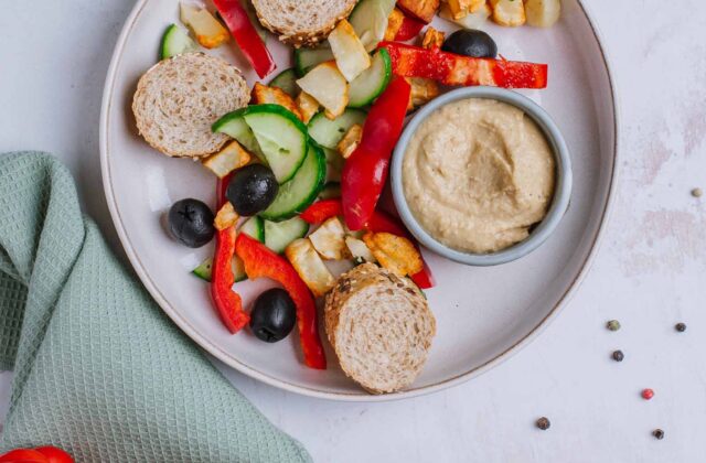 Śniadaniowy bowl z pieczonym halloumi, papryką, ogórkiem i oliwkami, hummus, bagietka graham
